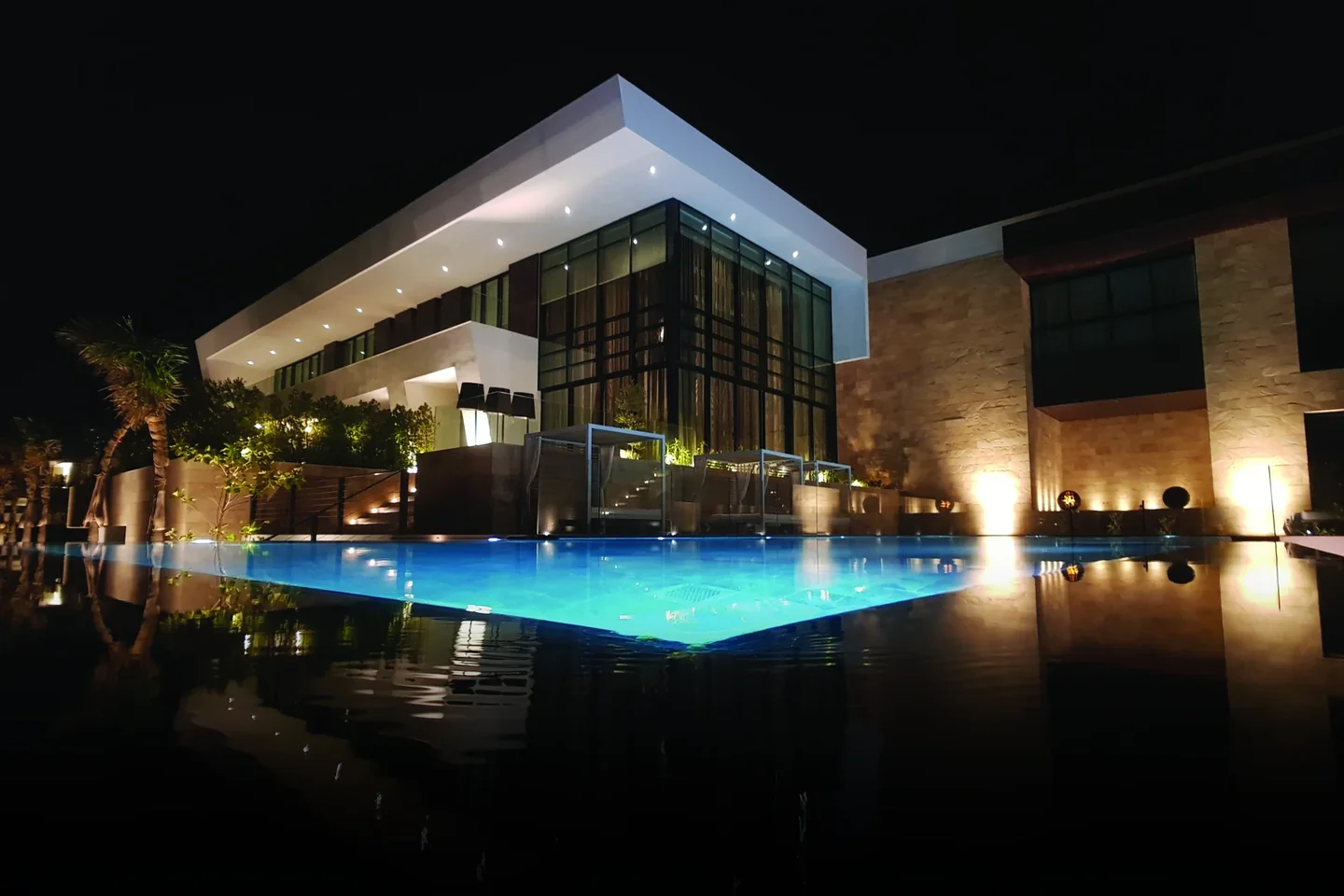 Modern villa and illuminated pool at night